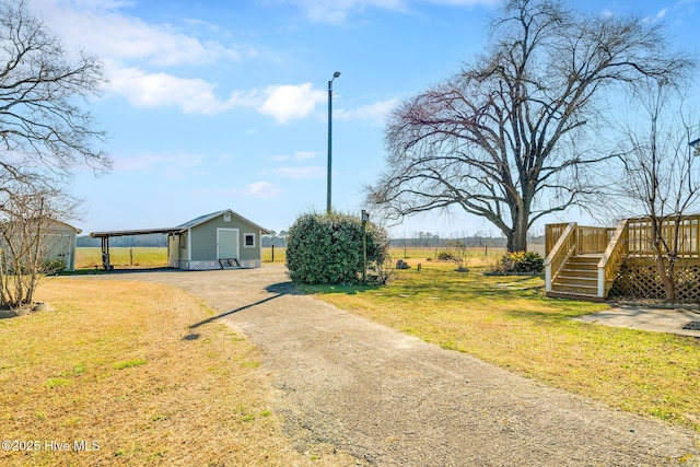 exterior space featuring driveway, stairway, a rural view, a deck, and an outdoor structure