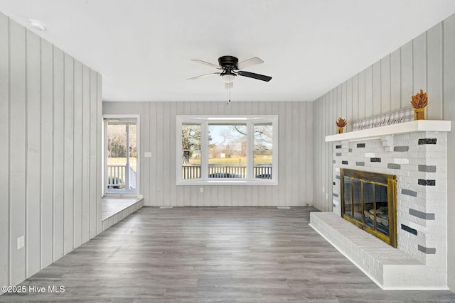 unfurnished living room featuring a brick fireplace, ceiling fan, and wood finished floors