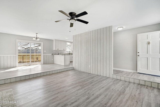 unfurnished living room featuring a ceiling fan and light wood-style floors