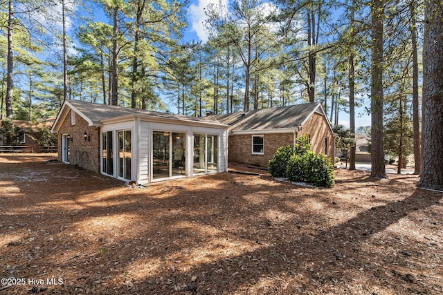 back of house with a sunroom and brick siding