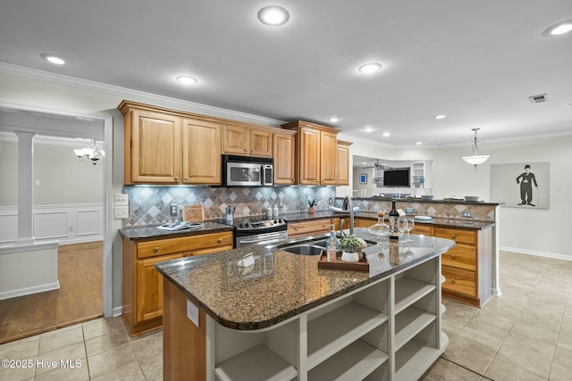 kitchen featuring brown cabinets, a kitchen island with sink, stainless steel appliances, open shelves, and a sink