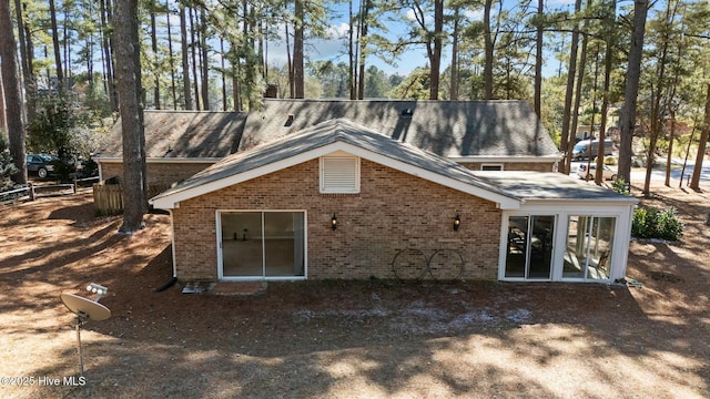 rear view of property with brick siding, fence, and a chimney