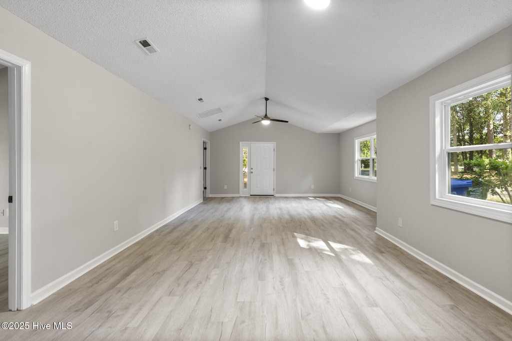 empty room featuring light hardwood / wood-style flooring, ceiling fan, a textured ceiling, and lofted ceiling