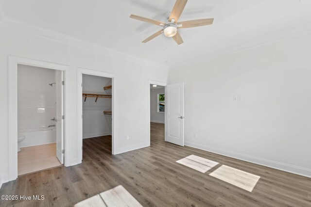 211 NE 78th St, Oak Island, NC 28465 - unfurnished bedroom with ornamental molding, wood finished floors, a spacious closet, a closet, and baseboards