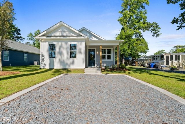 211 NE 78th St, Oak Island, NC 28465 - view of front of house featuring a front yard, cooling unit, and board and batten siding