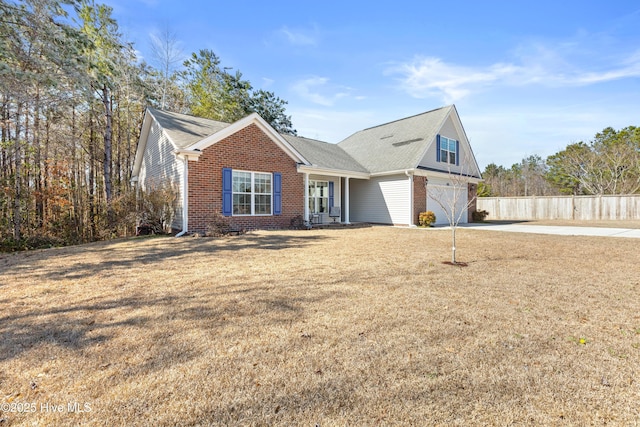 view of front facade with brick siding, a front yard, fence, a garage, and driveway