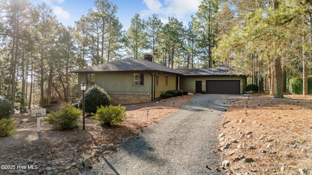 ranch-style house featuring driveway, an attached garage, and a chimney