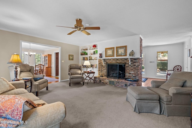 living room with built in features, ornamental molding, carpet flooring, a brick fireplace, and ceiling fan with notable chandelier