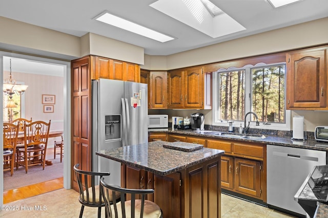 kitchen featuring a center island, a breakfast bar, stainless steel appliances, a sink, and dark stone countertops