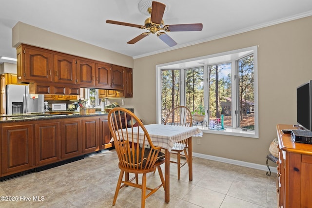 dining space featuring light tile patterned floors, baseboards, a ceiling fan, and ornamental molding