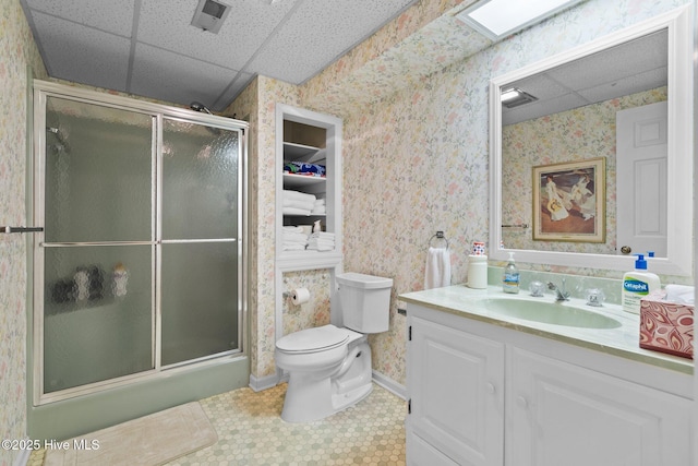 bathroom with vanity, a shower stall, toilet, and wallpapered walls