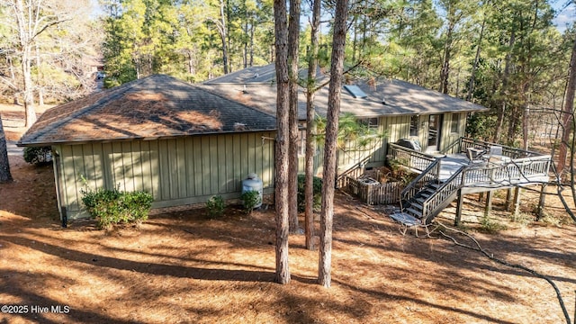 view of home's exterior featuring board and batten siding, roof with shingles, stairway, and a wooden deck