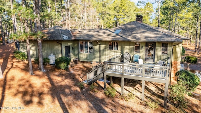 rear view of property with a shingled roof and a chimney