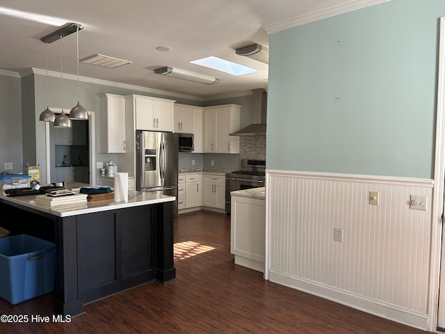 kitchen with pendant lighting, light countertops, appliances with stainless steel finishes, white cabinets, and wall chimney range hood