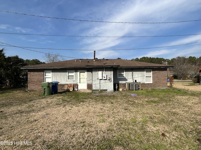 back of house featuring brick siding, a lawn, and central air condition unit