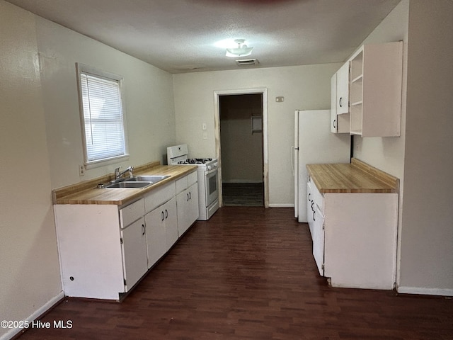 kitchen featuring white appliances, white cabinets, dark wood-type flooring, light countertops, and a sink