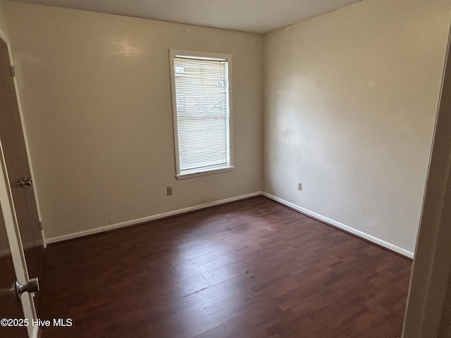 spare room with dark wood-style flooring and baseboards