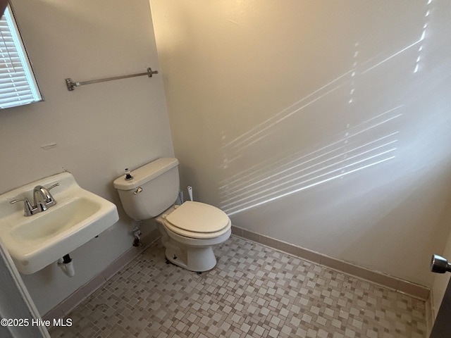 bathroom featuring baseboards, a sink, and toilet