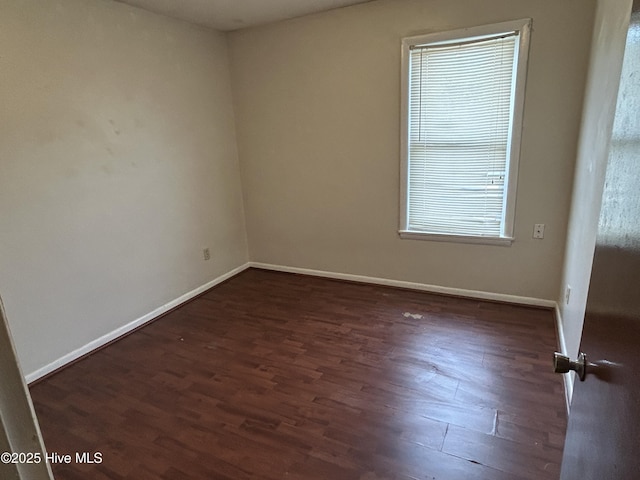 empty room with dark wood-style flooring and baseboards