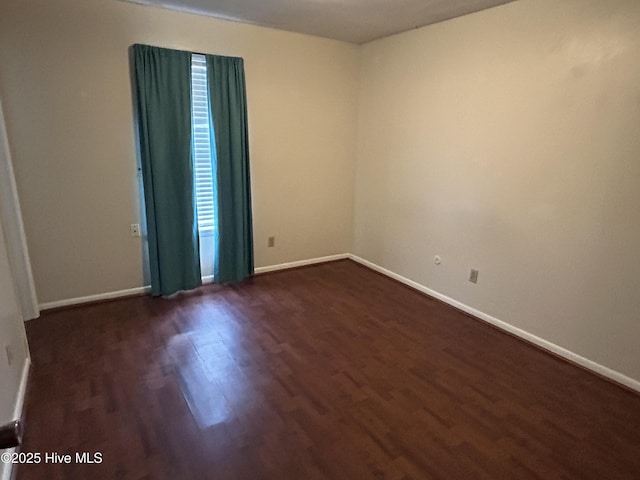 unfurnished room featuring baseboards and dark wood-style flooring