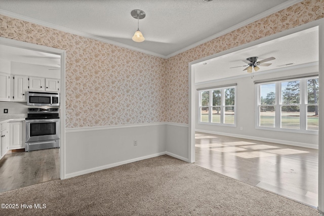 interior space with hanging light fixtures, stainless steel appliances, a textured ceiling, white cabinets, and crown molding