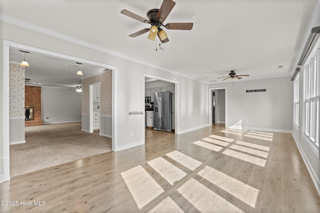 empty room featuring ceiling fan, hardwood / wood-style flooring, crown molding, and a fireplace