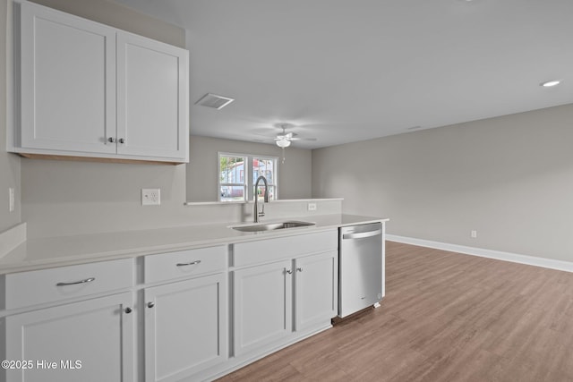 kitchen with light countertops, a peninsula, a sink, and dishwasher