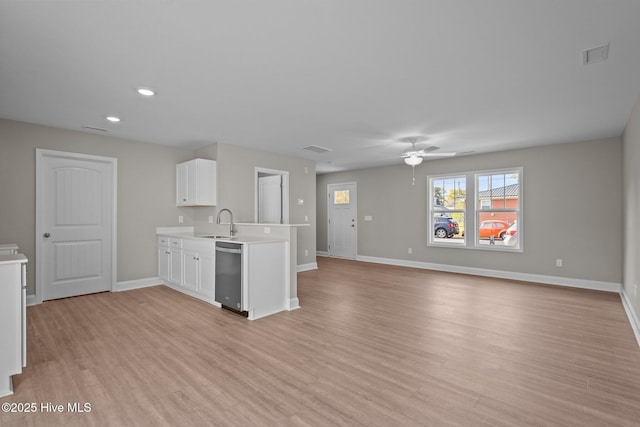 kitchen featuring light countertops, light wood finished floors, stainless steel dishwasher, and a peninsula