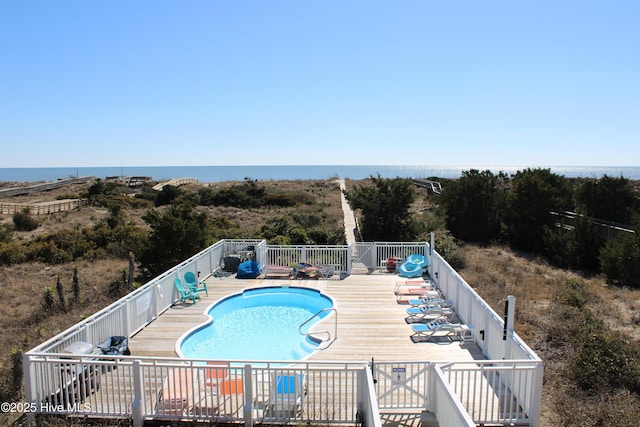 community pool featuring a water view, fence, and a patio