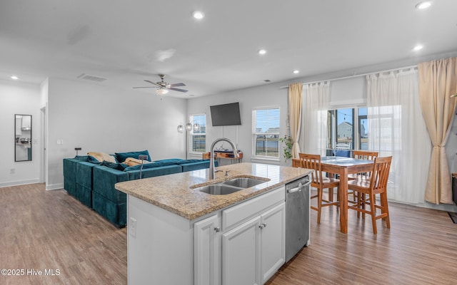 kitchen with dishwasher, light hardwood / wood-style floors, sink, white cabinetry, and a kitchen island with sink