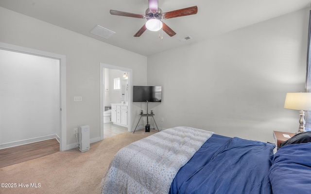 bedroom with ensuite bathroom, ceiling fan, and light colored carpet