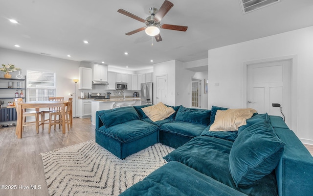 living room with sink, ceiling fan, and light hardwood / wood-style floors