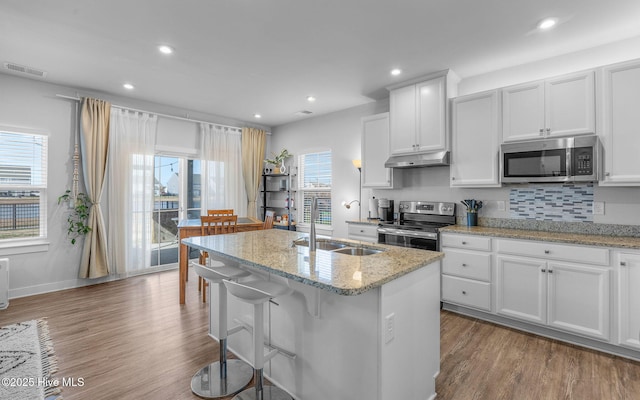 kitchen featuring sink, appliances with stainless steel finishes, white cabinets, and an island with sink