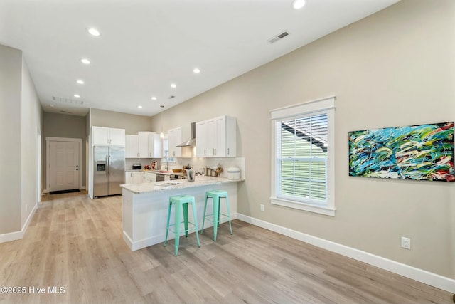 kitchen with stainless steel refrigerator with ice dispenser, visible vents, decorative backsplash, white cabinetry, and a peninsula