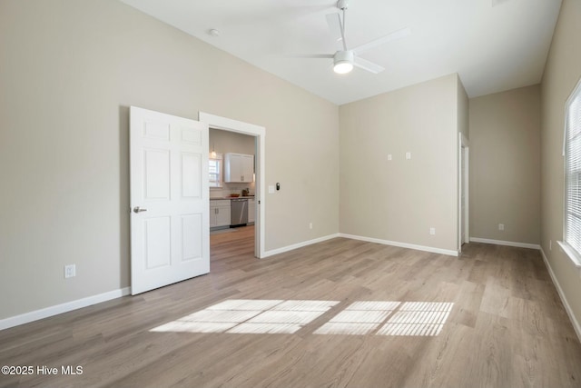 empty room with a ceiling fan, light wood-style flooring, and baseboards