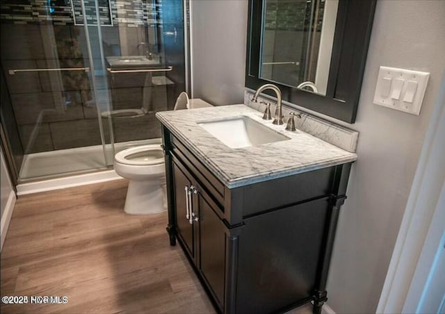 full bathroom with a stall shower, vanity, toilet, and wood finished floors