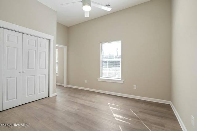 unfurnished bedroom with light wood-style floors, a ceiling fan, baseboards, and a closet