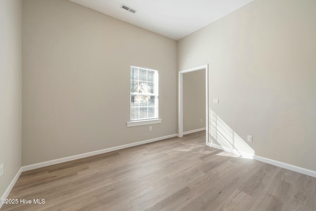 empty room with light wood-style flooring, visible vents, and baseboards