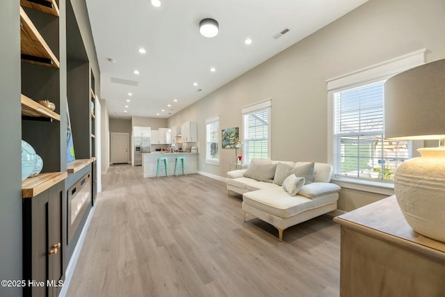 living room with recessed lighting, a healthy amount of sunlight, and light wood-style flooring