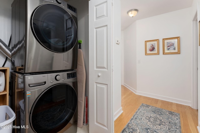 laundry area with stacked washer and dryer and light hardwood / wood-style floors