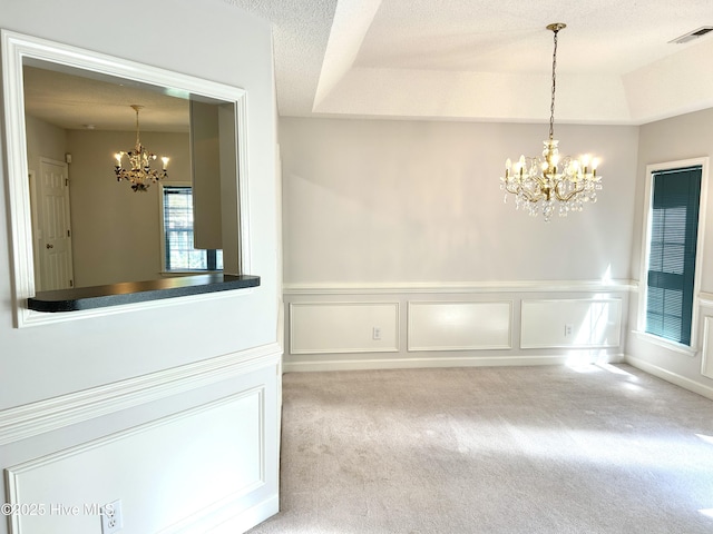 6237 Sentry Oaks Dr, Wilmington, NC 28409 - unfurnished dining area featuring a chandelier, carpet floors, wainscoting, a textured ceiling, and a decorative wall