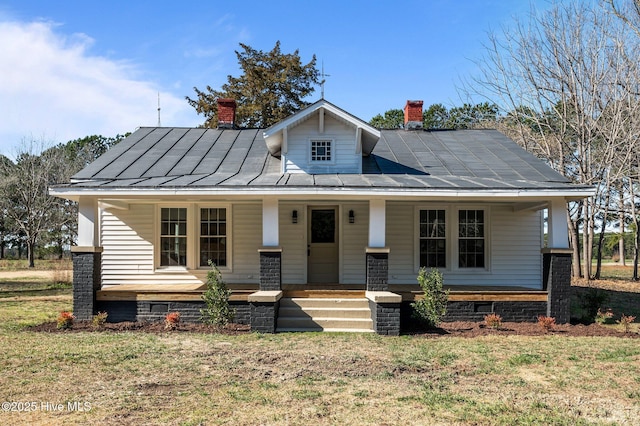 bungalow-style home with a porch, a standing seam roof, and a chimney