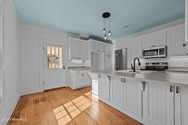 kitchen featuring a breakfast bar, white cabinetry, light countertops, appliances with stainless steel finishes, and hanging light fixtures