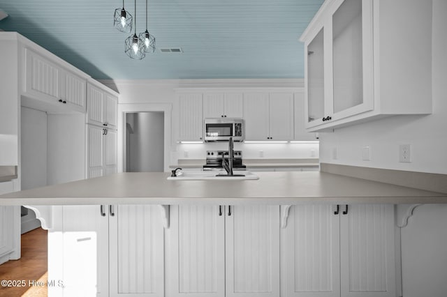 kitchen featuring stainless steel appliances, white cabinets, hanging light fixtures, and a kitchen breakfast bar