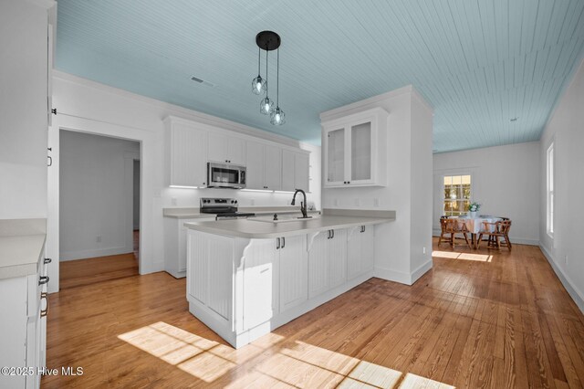 kitchen featuring light countertops, appliances with stainless steel finishes, glass insert cabinets, white cabinetry, and a peninsula