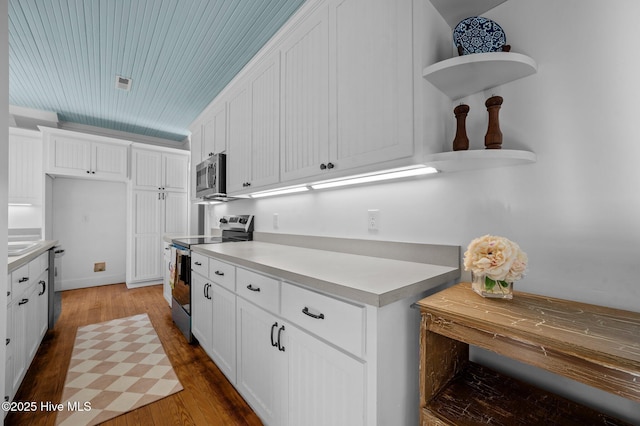 kitchen with white cabinetry, appliances with stainless steel finishes, light countertops, and dark wood-style flooring