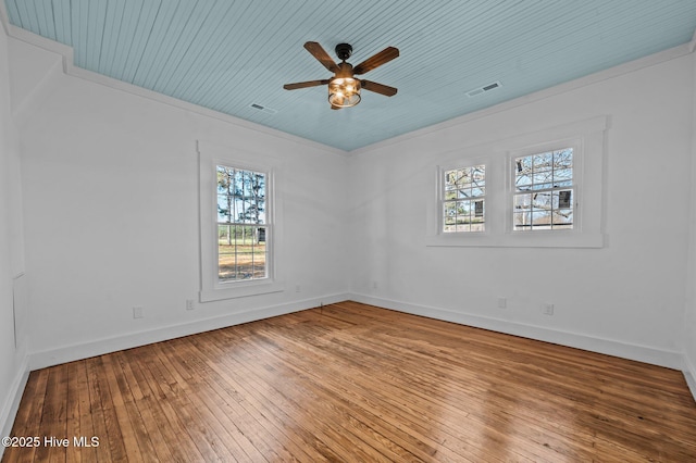 spare room featuring a ceiling fan, hardwood / wood-style flooring, visible vents, and baseboards