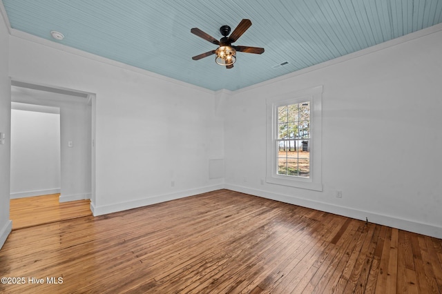 spare room with baseboards, visible vents, a ceiling fan, hardwood / wood-style flooring, and ornamental molding