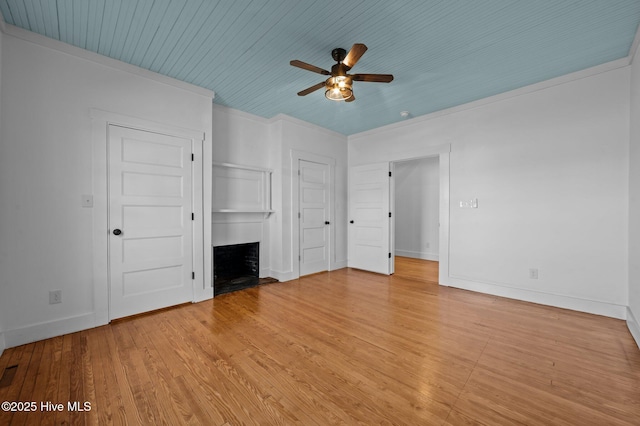 unfurnished bedroom featuring a fireplace with raised hearth, light wood-style flooring, and baseboards