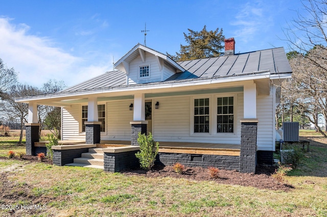 bungalow-style home featuring a chimney, metal roof, a standing seam roof, a porch, and a front yard